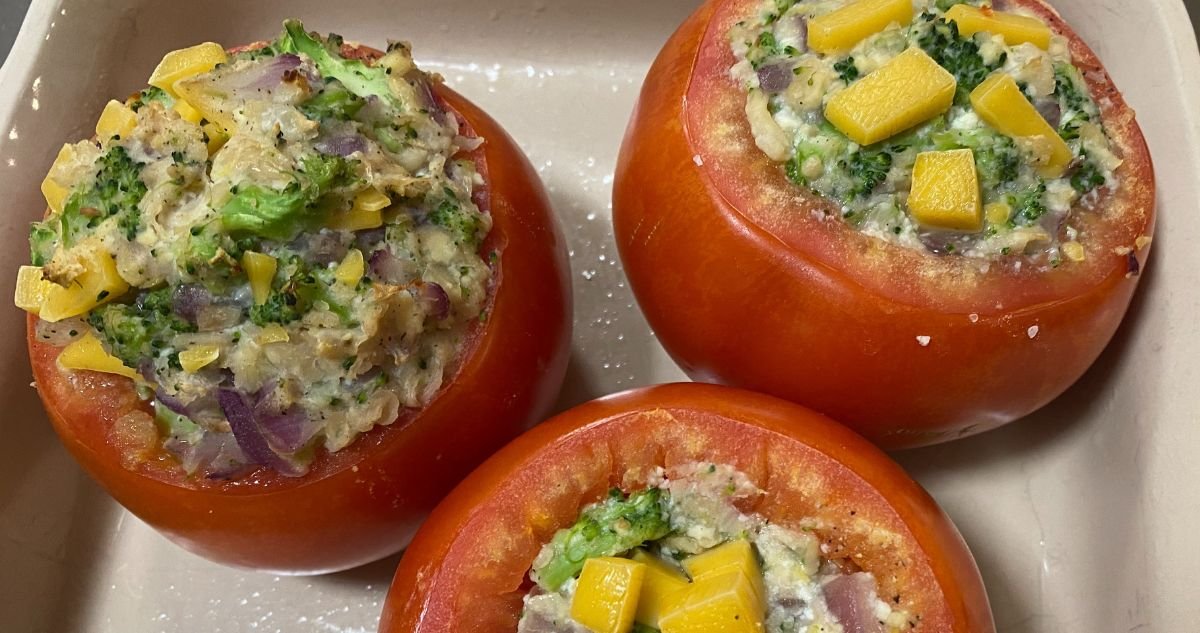 over head shot of three stuffed red bell peppers in dish.