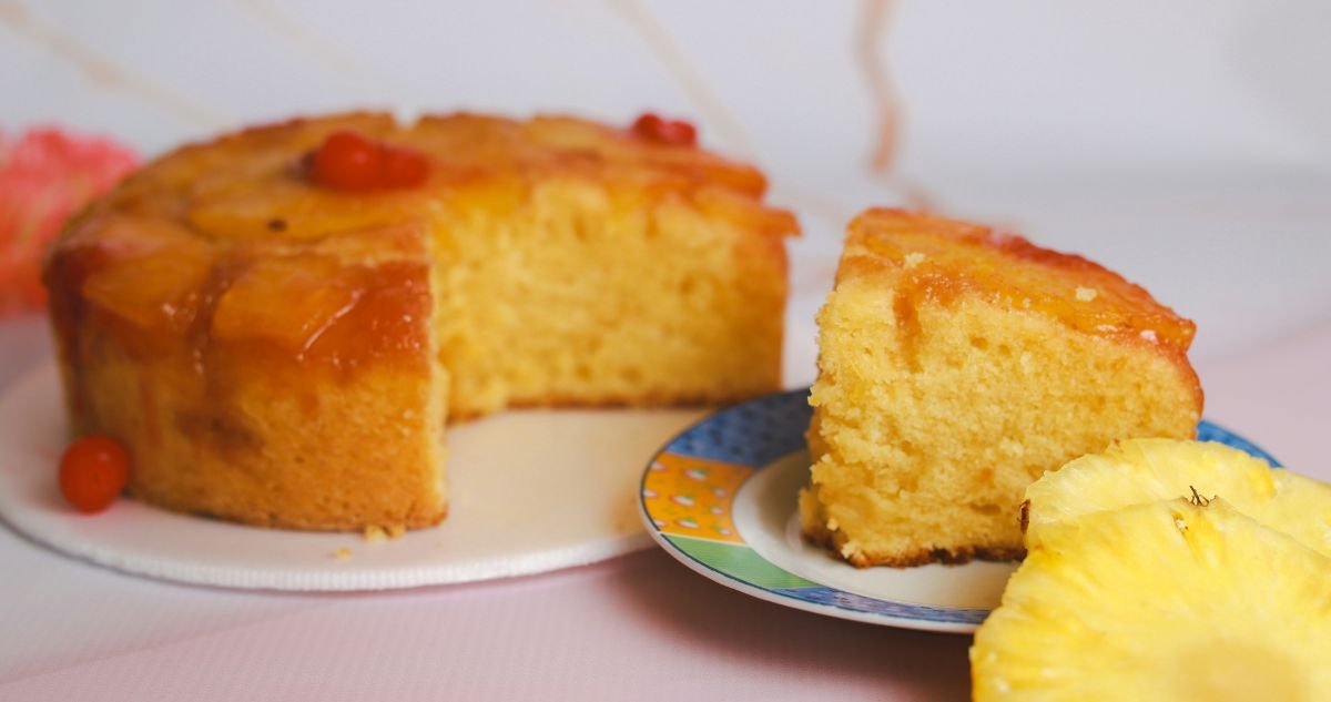 Upside-Down Cake topped with maraschino cherries with a slice on a plate.